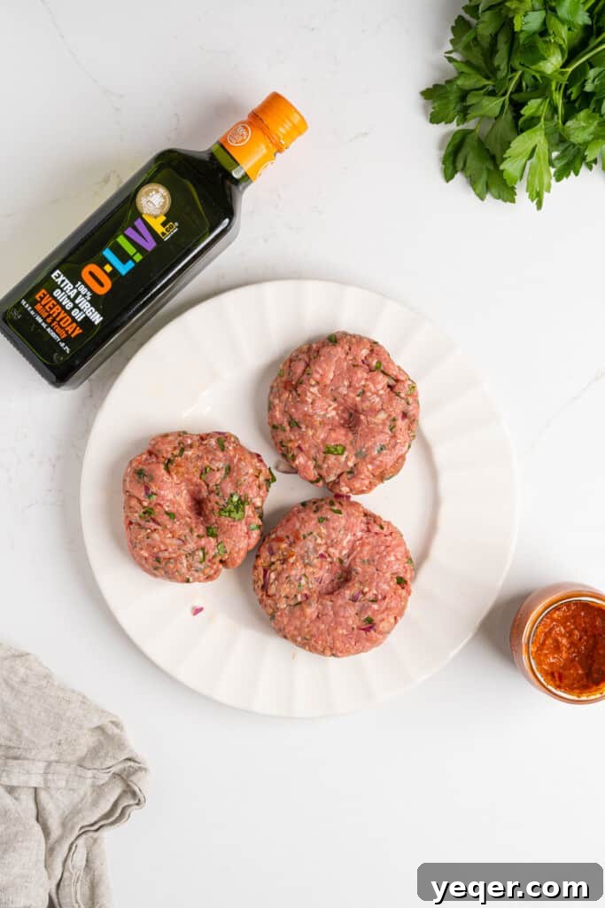 Spicy Harissa Burgers 5 Harissa burger patties sizzling on a hot grill, showing a perfect sear and smoky char.