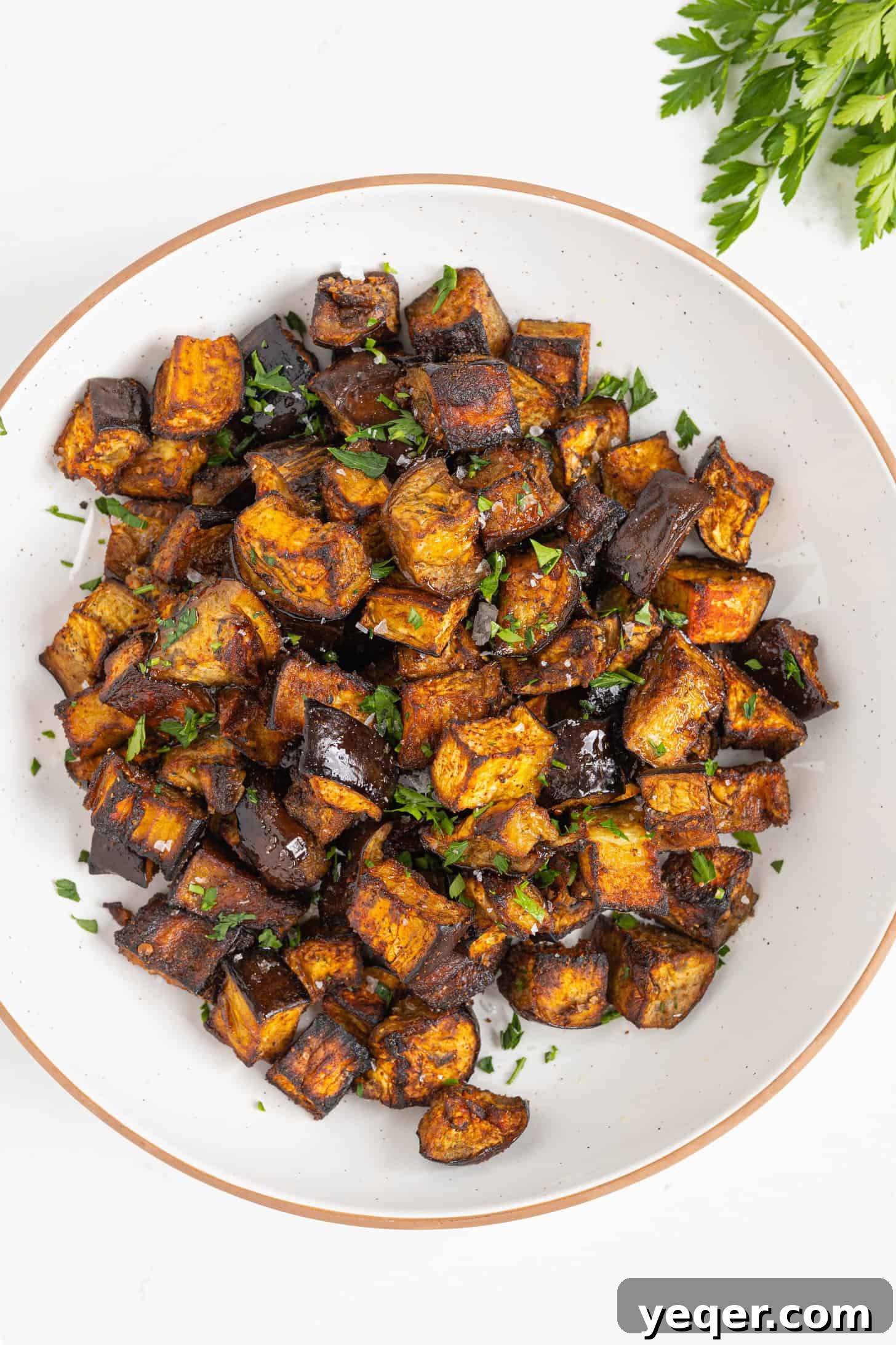 North African Roasted Aubergine in Minutes 7 Close-up of roasted Moroccan eggplant cubes in a ceramic bowl, glistening with olive oil and spices, inviting a taste.