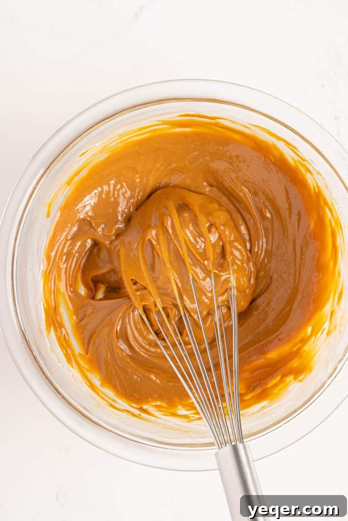 Three-Ingredient Bliss: Dulce de Leche Ice Cream 4 A bowl of thick dulce de leche being smoothed with a whisk