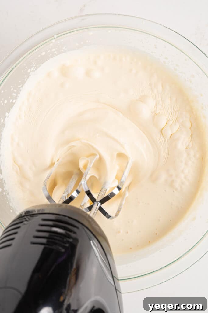Three-Ingredient Bliss: Dulce de Leche Ice Cream 5 Heavy cream being whipped to soft peaks in a large mixing bowl