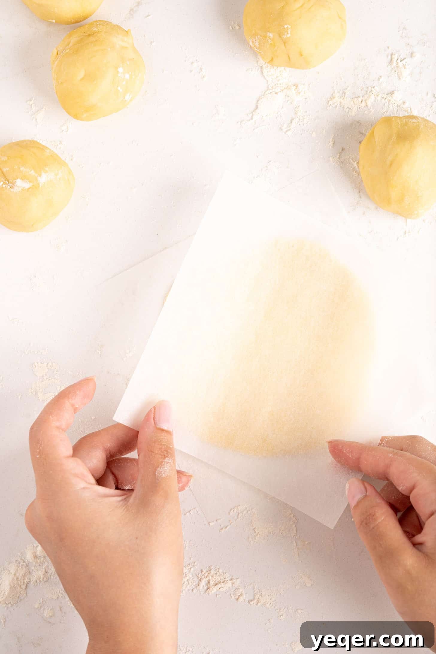 Five-Ingredient Wonder Empanada Dough 19 A close-up of hands expertly kneading a soft ball of empanada dough on a floured wooden surface, showing the smooth and pliable texture.