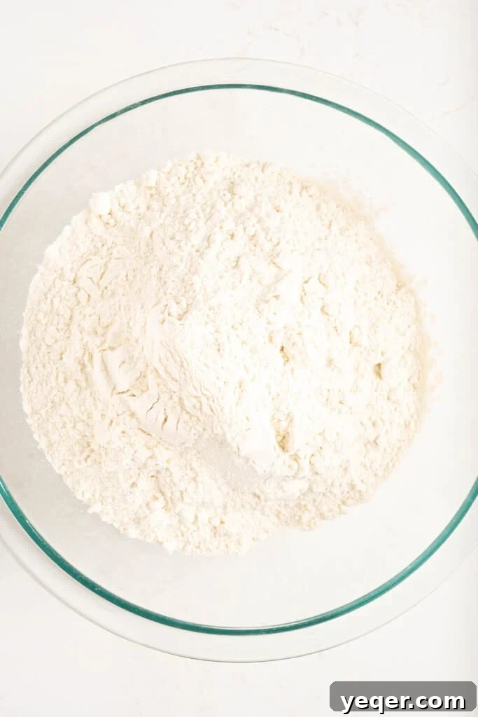 Five-Ingredient Wonder Empanada Dough 5 A large ceramic bowl filled with finely sifted all-purpose flour, ready for the next step in dough preparation.