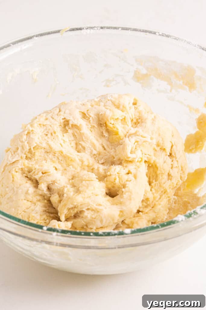 Five-Ingredient Wonder Empanada Dough 7 Hands gently working a mixture of wet and dry ingredients in a bowl, showing the initial stages of empanada dough formation.