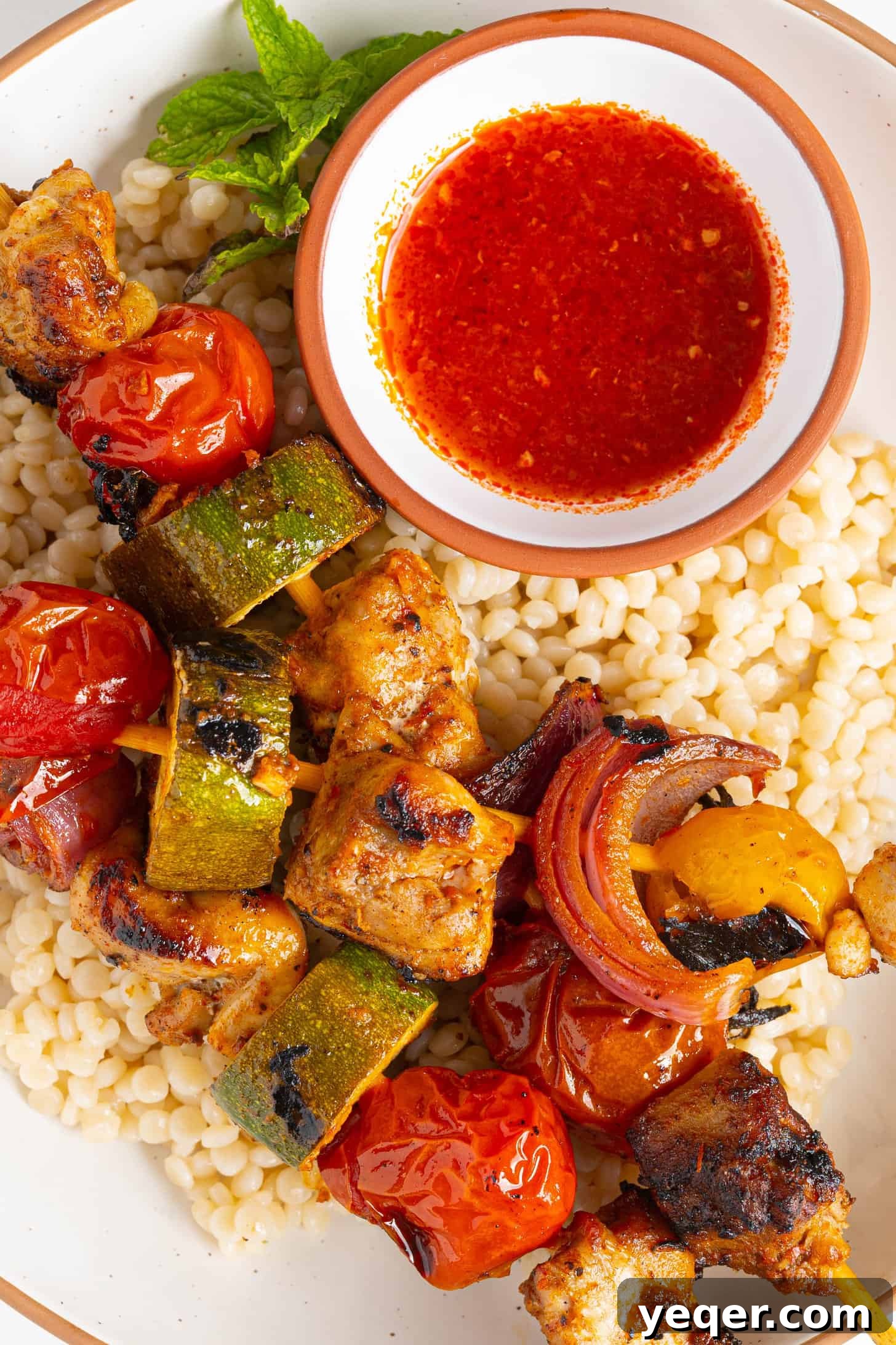 Flavor-Packed Harissa Chicken Skewers in 30 Minutes 2 harissa chicken skewers on a plate of couscous, a vibrant and flavorful North African dish
