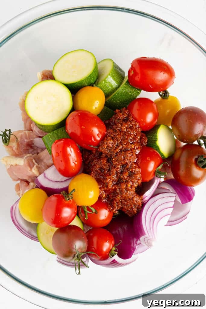 Flavor-Packed Harissa Chicken Skewers in 30 Minutes 6 chicken pieces and chopped vegetables in a bowl