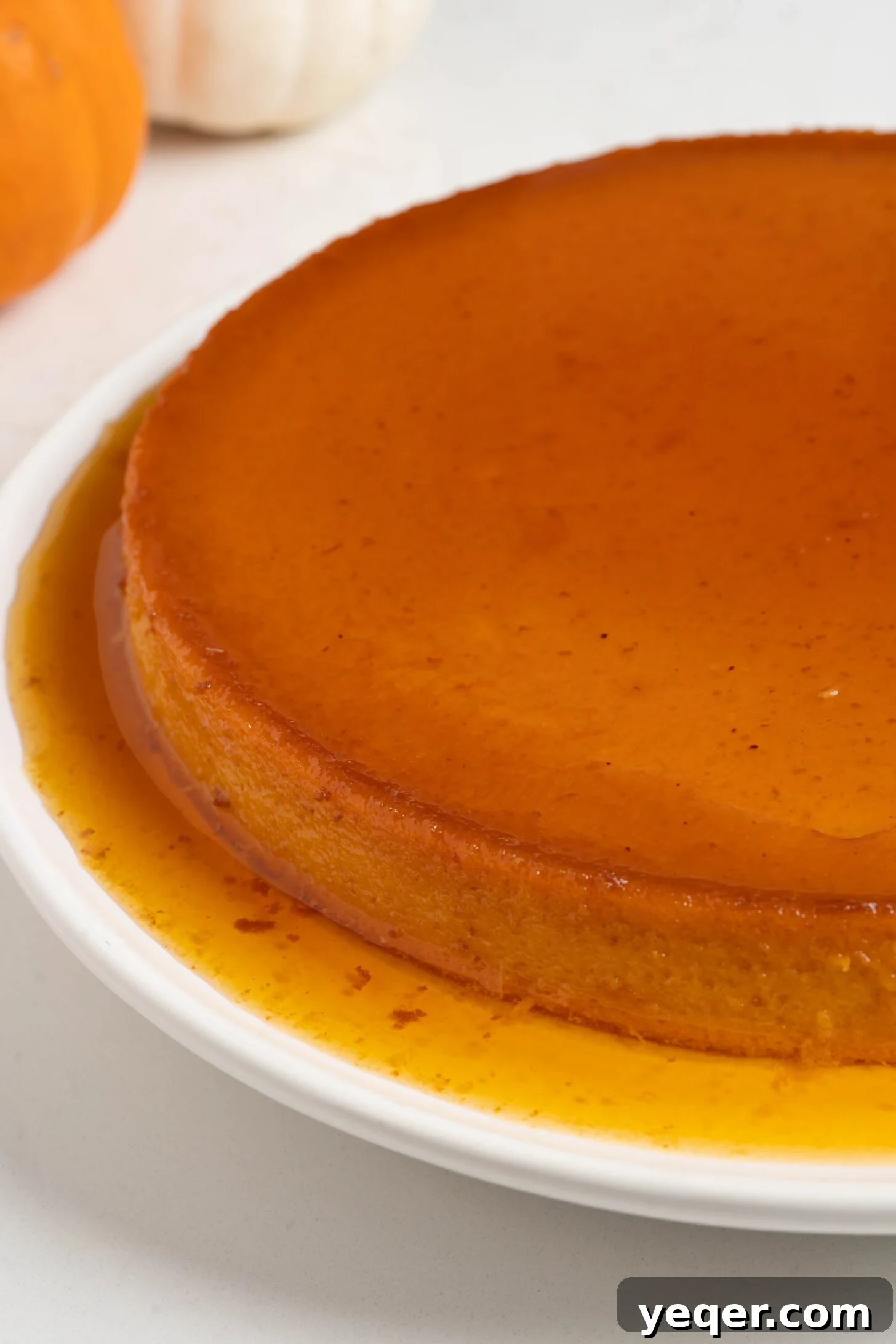 Golden Pumpkin Caramel Flan 12 A generous slice of pumpkin flan garnished with a sprinkle of cinnamon on a white plate.