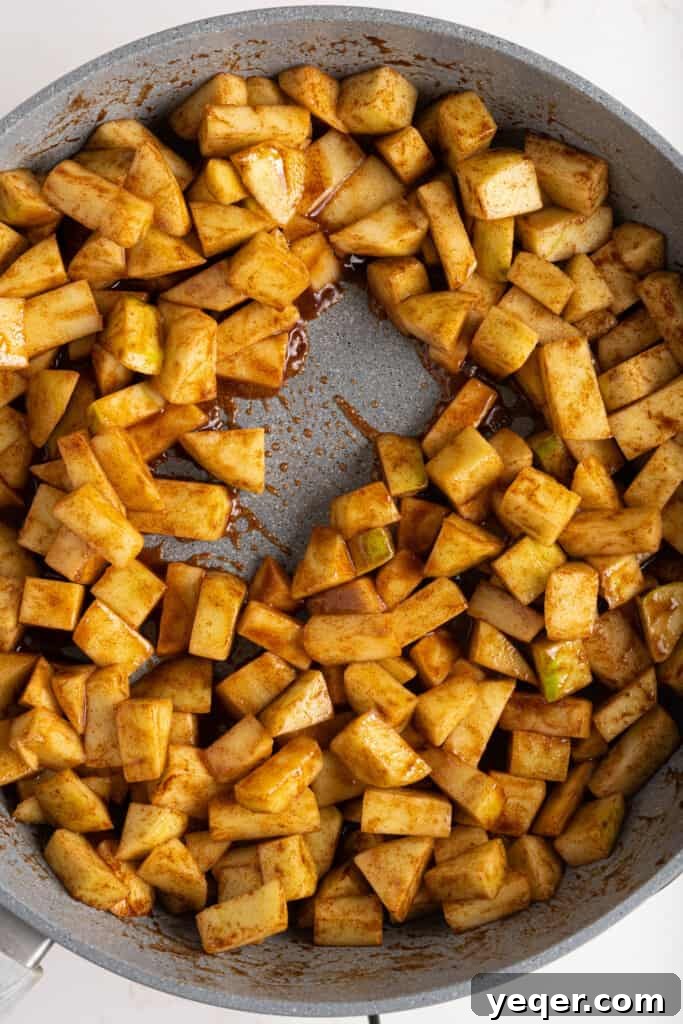 Golden Apple Pastry Pockets 5 Diced apples being gently tossed in a rich caramel sauce in a pan.