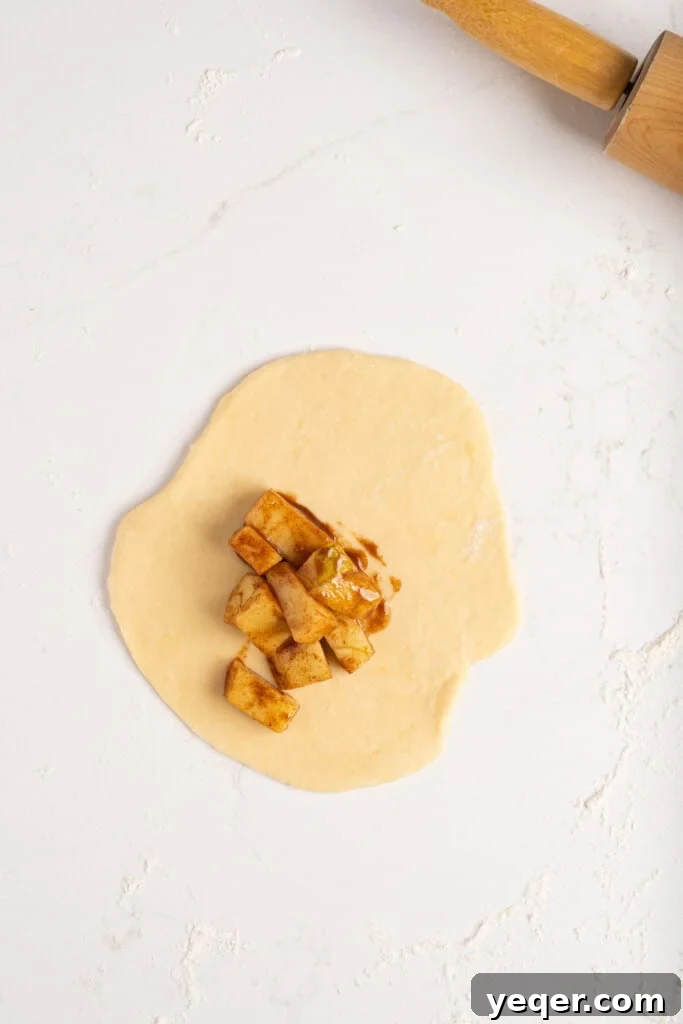 Golden Apple Pastry Pockets 6 A scoop of warm apple filling placed neatly on an empanada dough disc.
