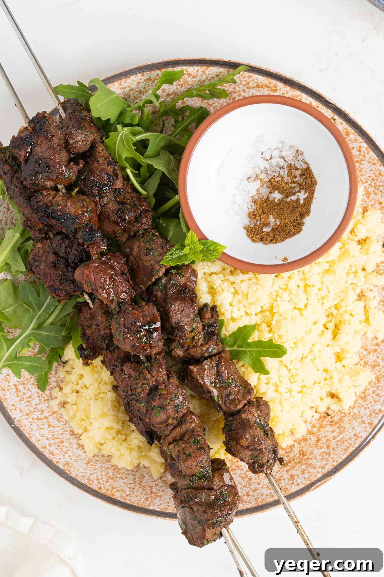 Char-Grilled Lamb Skewers with Tangy Preserved Lemon 2 A beautifully arranged plate of grilled Moroccan lamb kebabs, garnished with fresh herbs.