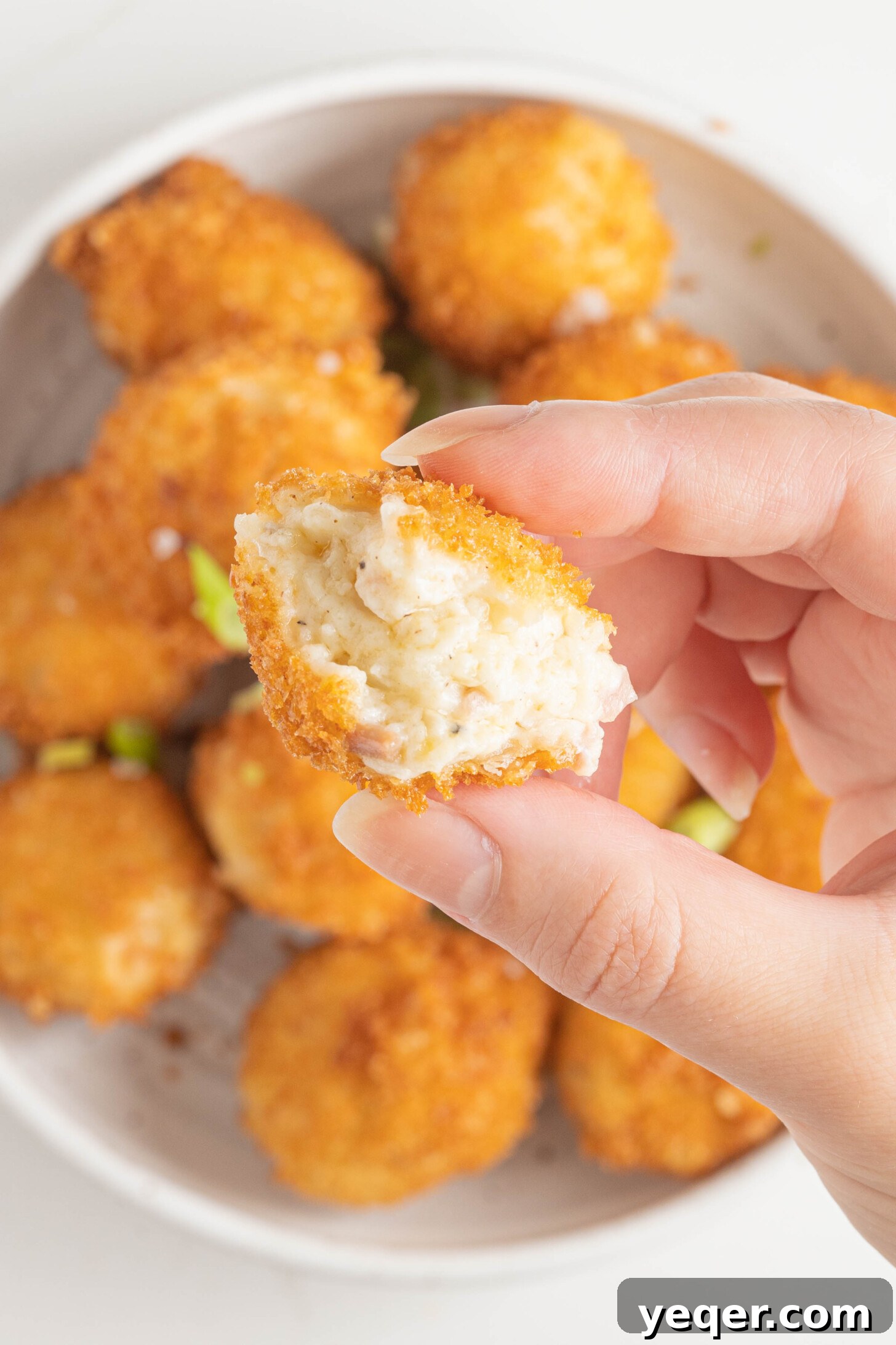 Golden Ham Croquettes 11 A hand holding a perfectly golden-brown Croqueta de Jamón, showcasing its enticing crispy texture.