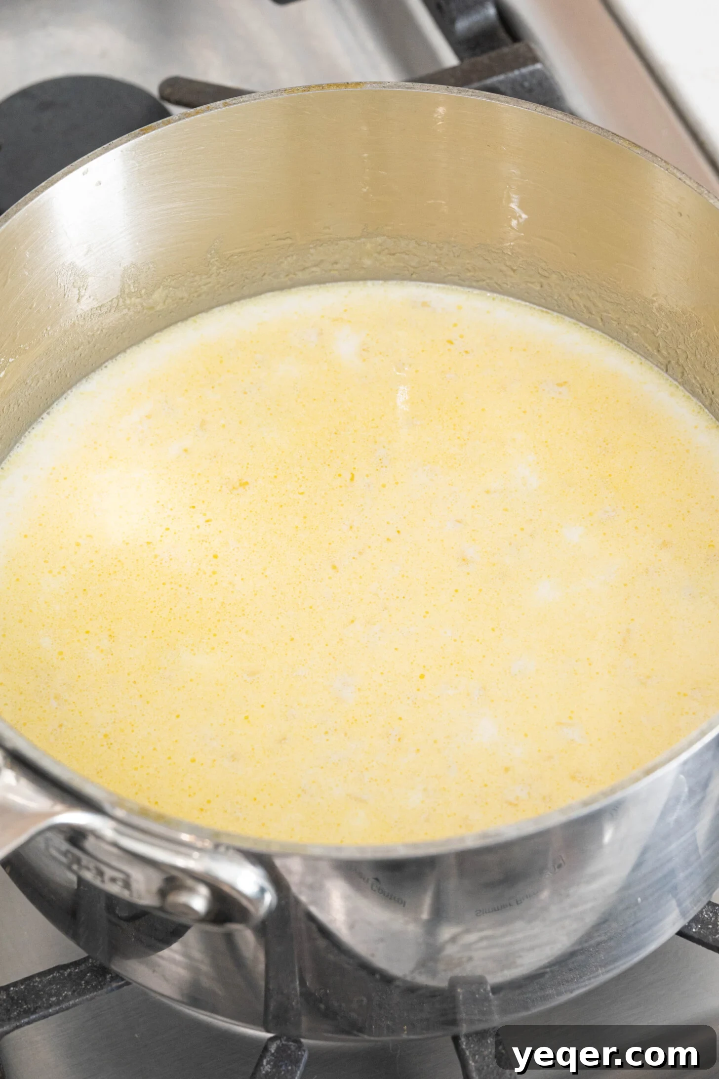 Golden Ham Croquettes 7 The rich and creamy béchamel sauce, infused with milk, butter, and onions, being stirred in a pot, ready for the next stage of croqueta preparation.