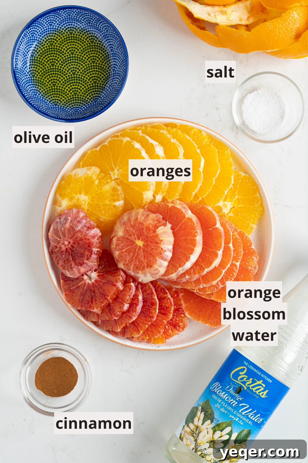 Quick Moroccan Orange Salad with Cinnamon Spice 3 Ingredients for Moroccan orange salad laid out: fresh oranges, olive oil, cinnamon, salt, and a bottle of orange blossom water.