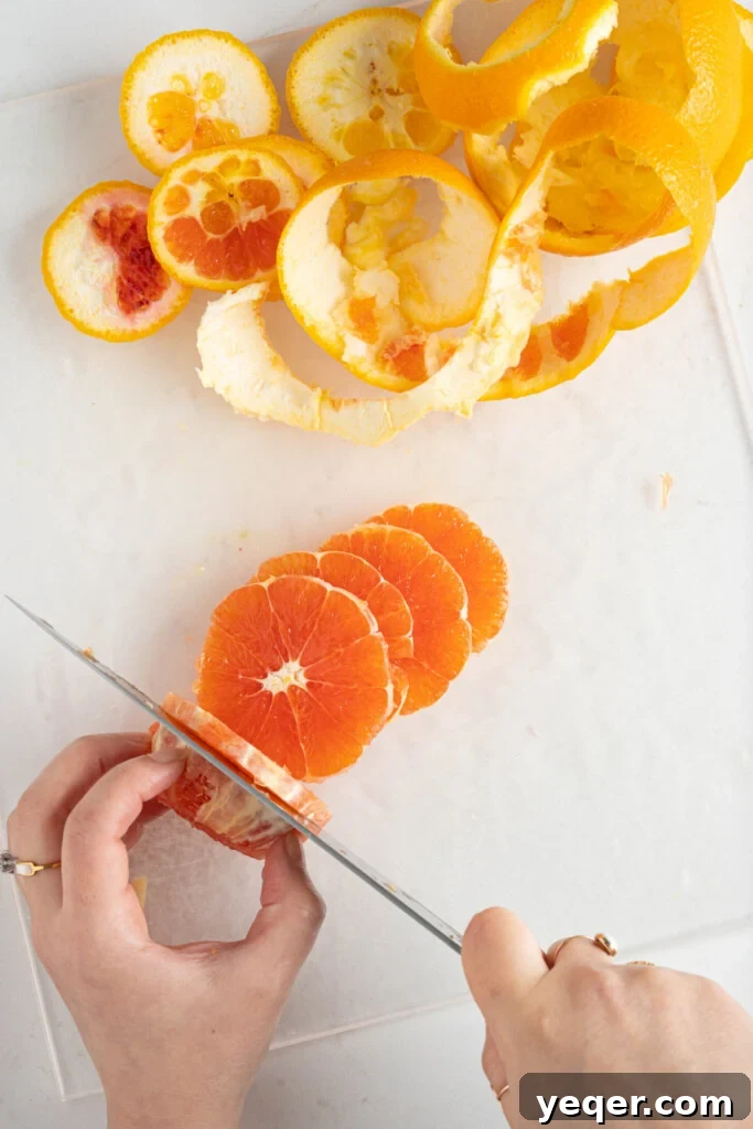 Quick Moroccan Orange Salad with Cinnamon Spice 5 Hands carefully slicing a peeled orange into uniform rounds on a cutting board.