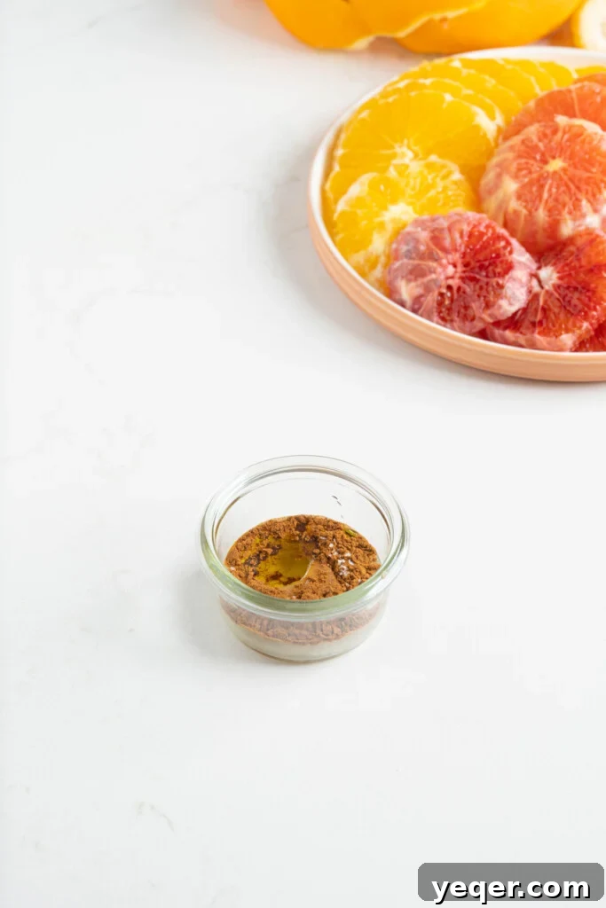 Quick Moroccan Orange Salad with Cinnamon Spice 6 A small glass jar filled with the prepared dressing, placed next to a plate of sliced oranges.