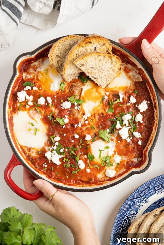 Speedy Moroccan Shakshuka 8 two hands holding shakshuka in a pan on a white counter