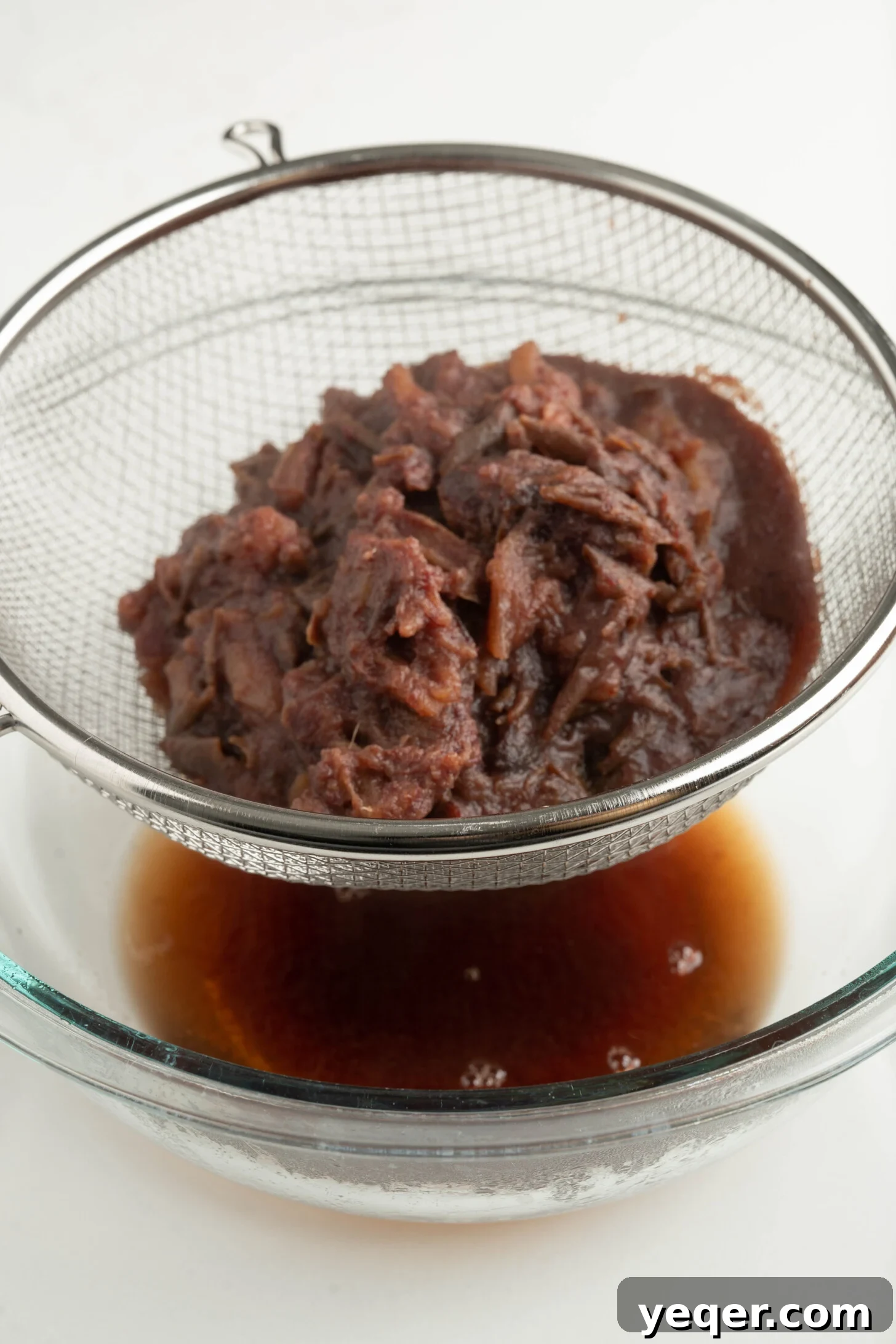 Pure Date Nectar 8 Straining the date liquid from the pulp using a mesh strainer into a bowl