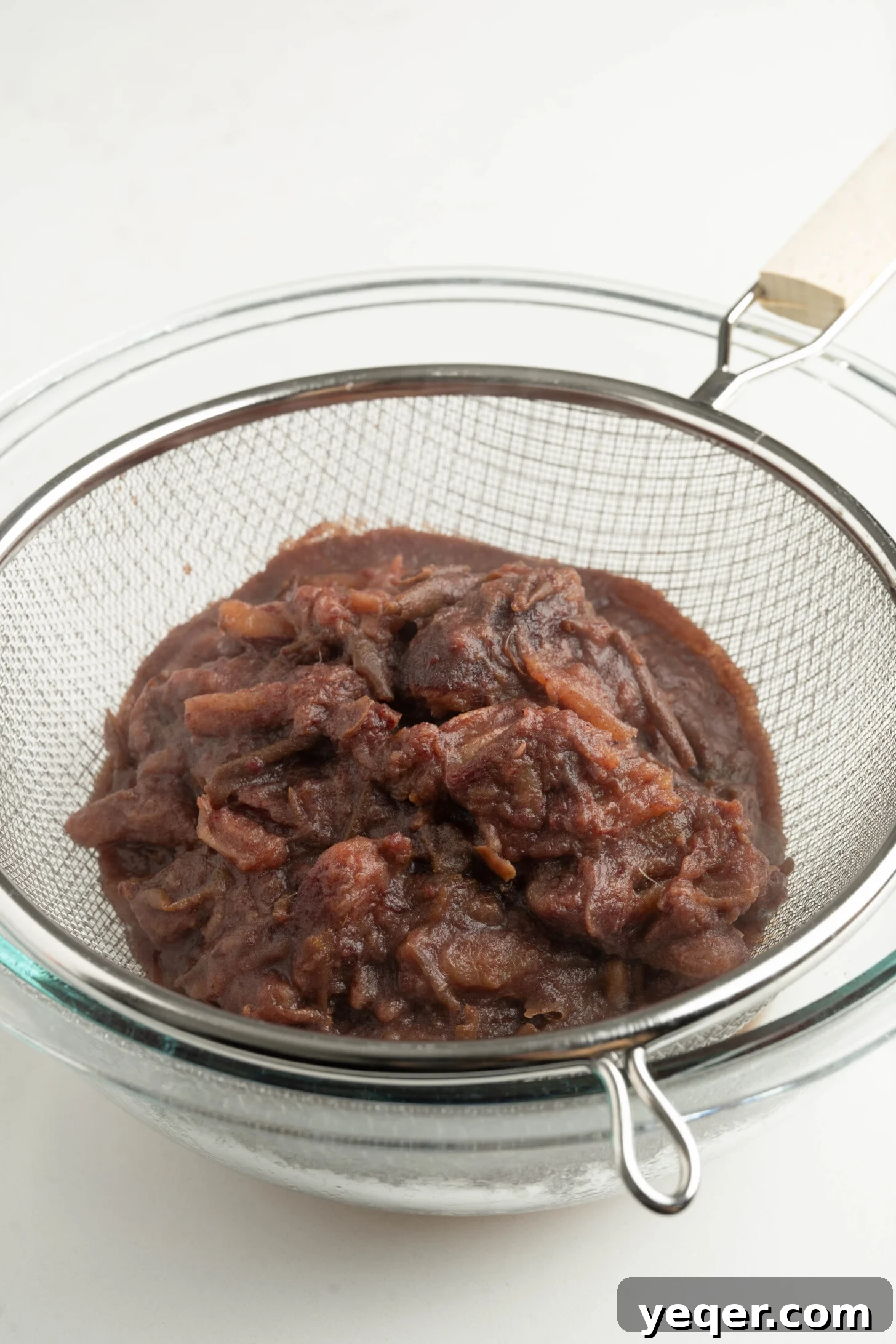 Pure Date Nectar 10 Close-up of date pulp being strained through a fine-mesh sieve, highlighting its texture