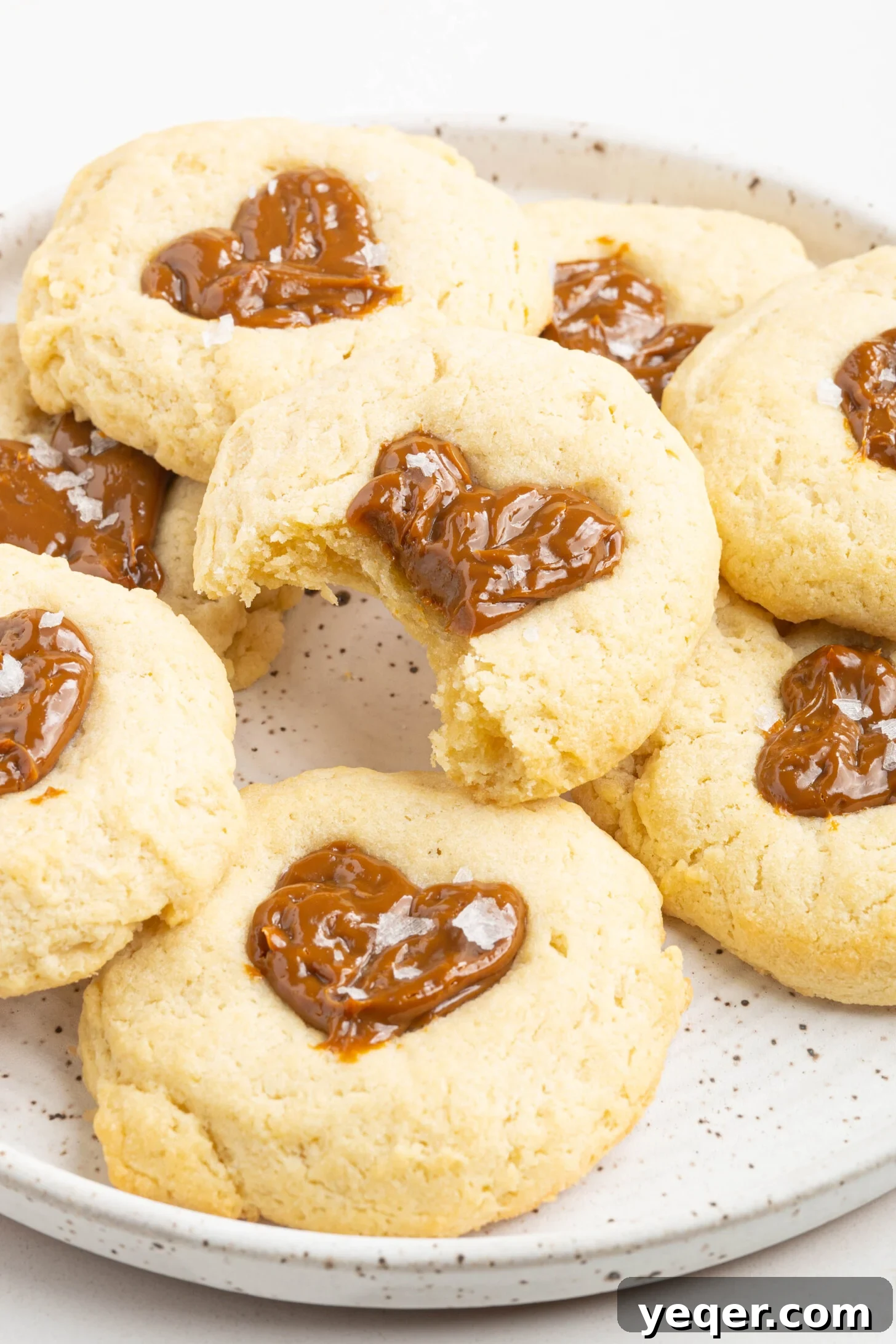 Easy Dulce de Leche Thumbprint Cookies 2 A beautifully arranged plate of Dulce de Leche heart-shaped thumbprint cookies, showcasing their golden edges and rich caramel centers.
