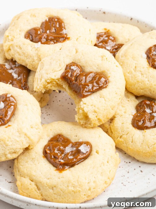 A plate of perfectly baked Dulce de Leche thumbprint cookies, showing off their golden edges and shiny caramel centers.