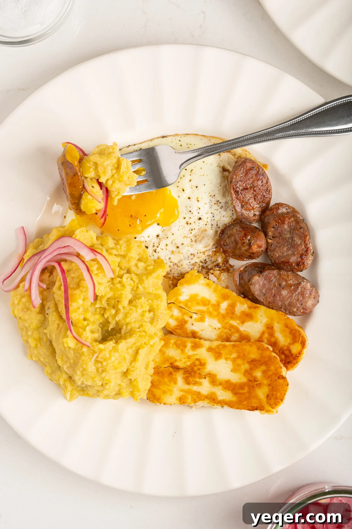Whip Up Dominican Mangu in 30 Minutes 7 A plate featuring Mangu, a fried egg, fried white cheese, and Dominican sausage, creating a complete breakfast.
