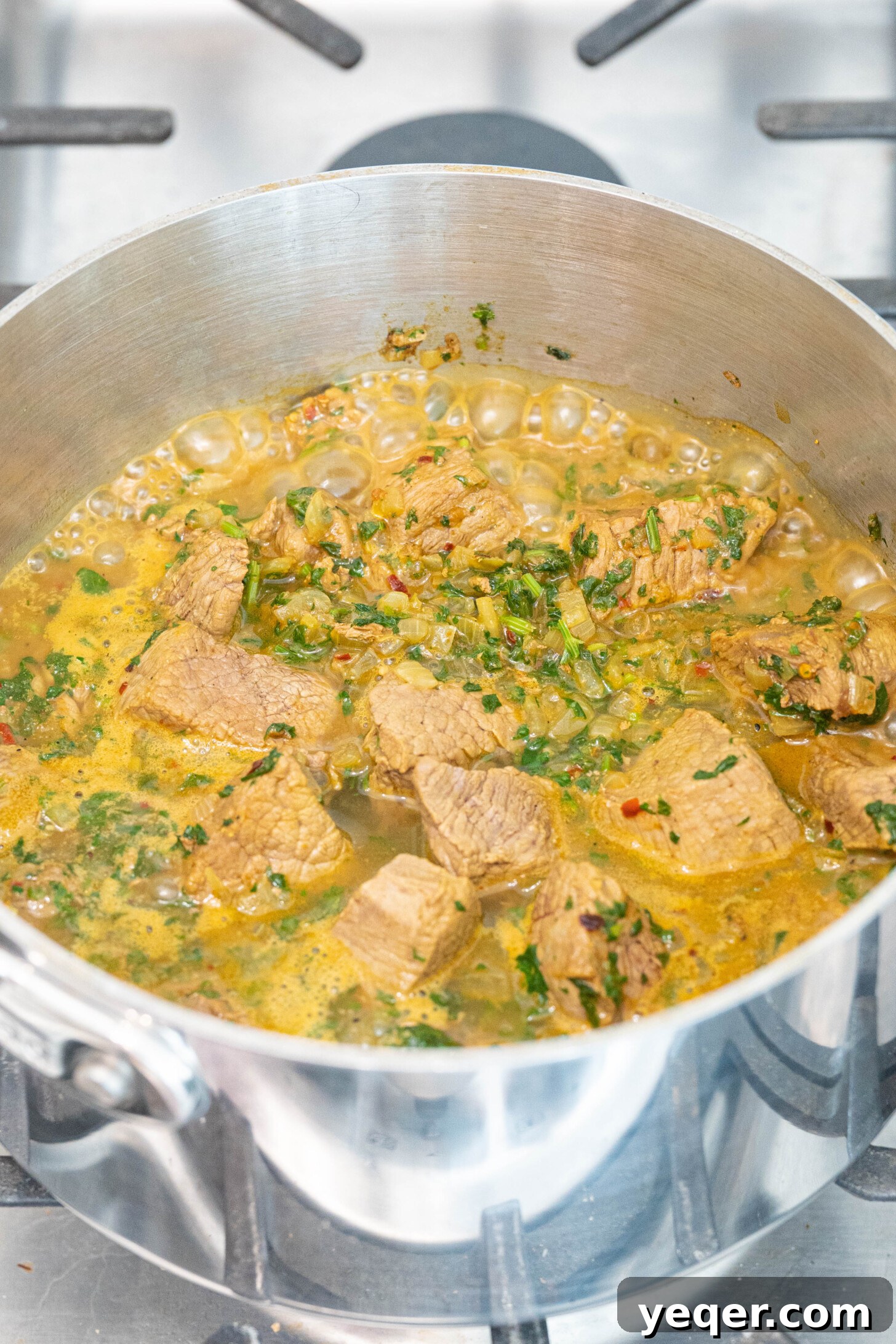 Moroccan Lamb Orzo Pilaf 6 A smaller saucepan with the seasoned lamb, onions, herbs, and water gently simmering on the stovetop.