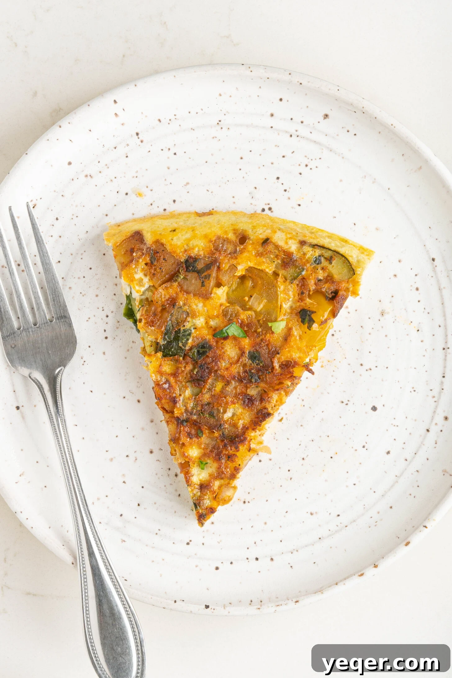Moroccan Golden Potato Frittata 2 a slice of a potato omelette, showcasing its layers of potatoes, vegetables, and fluffy eggs