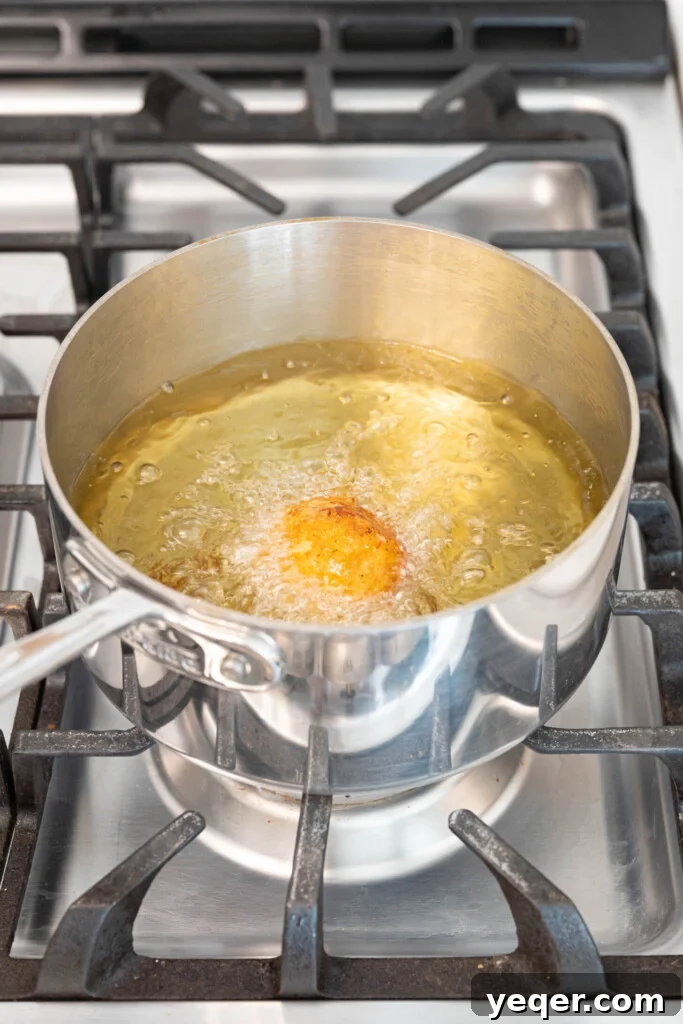 Golden Crispy Stuffed Potatoes 12 Golden-brown Papas Rellenas frying in bubbling hot oil, achieving a perfect crispy exterior.