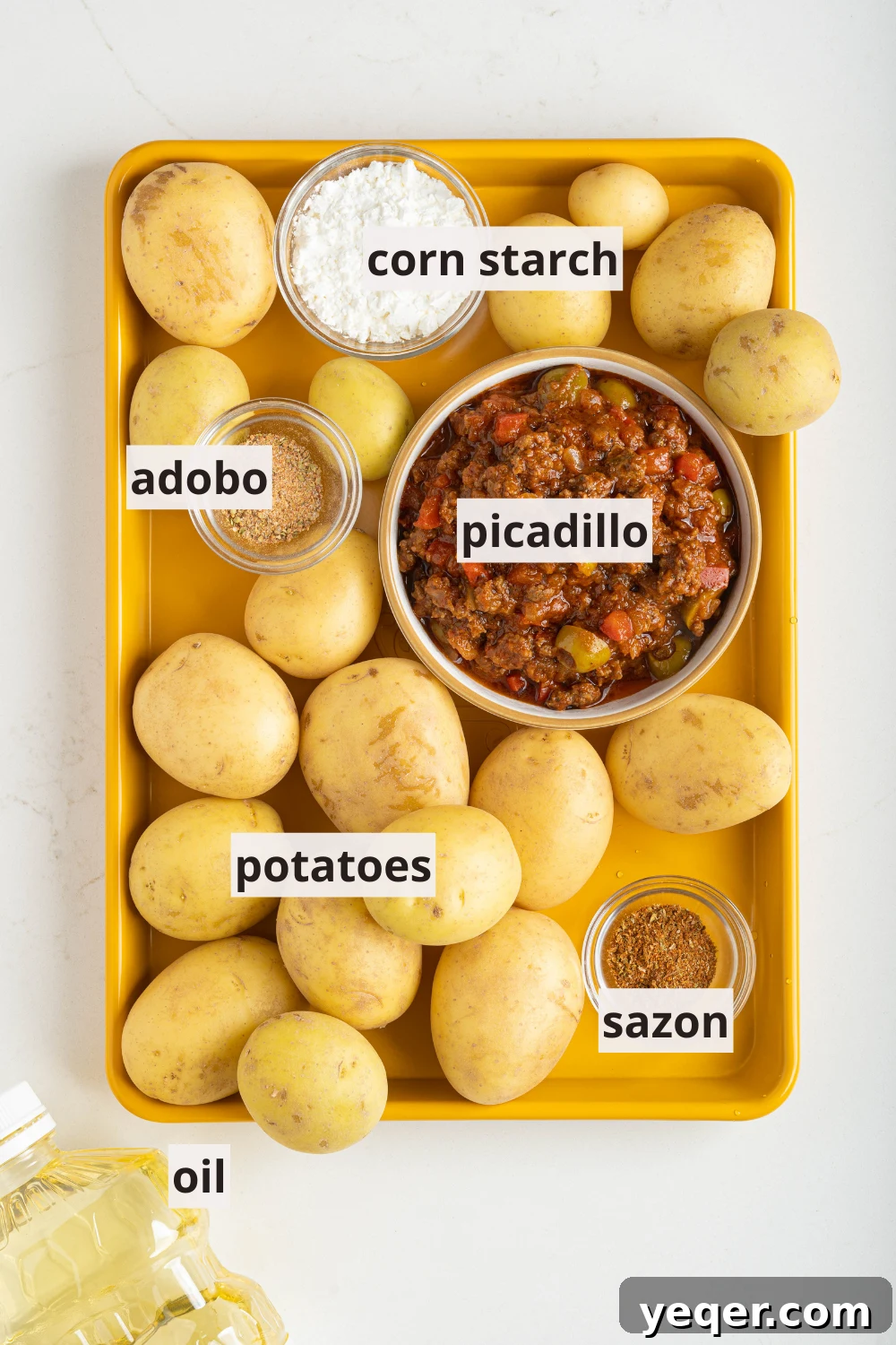 Golden Crispy Stuffed Potatoes 3 A tray filled with various ingredients for Papas Rellenas, including potatoes, prepared picadillo, corn starch, and seasonings.
