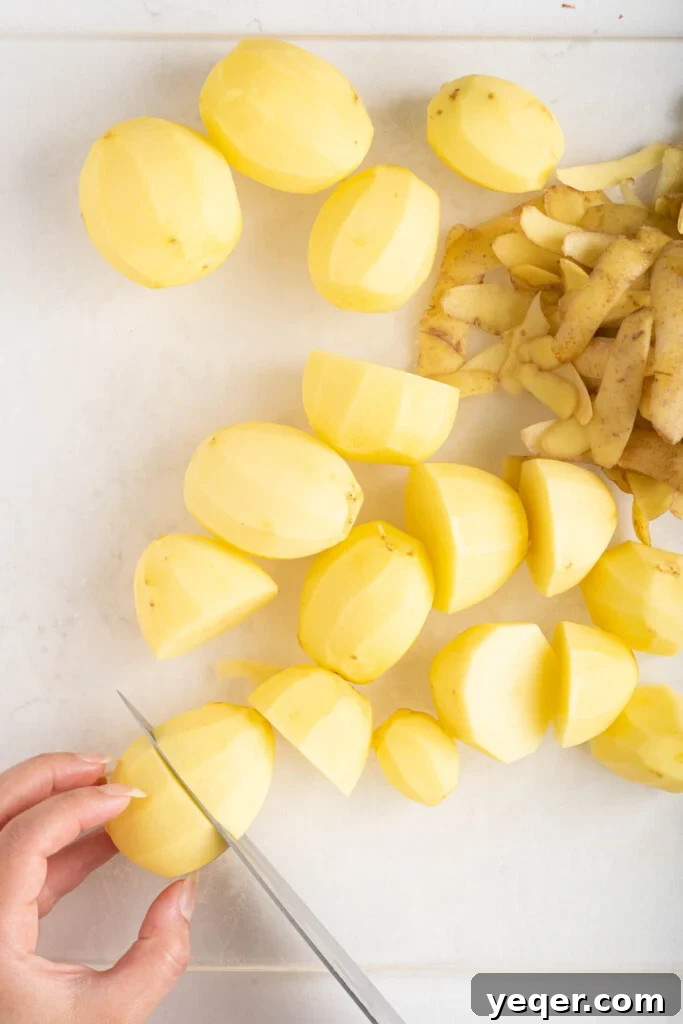Golden Crispy Stuffed Potatoes 6 Hands carefully chopping potatoes into uniform pieces with a knife on a cutting board.