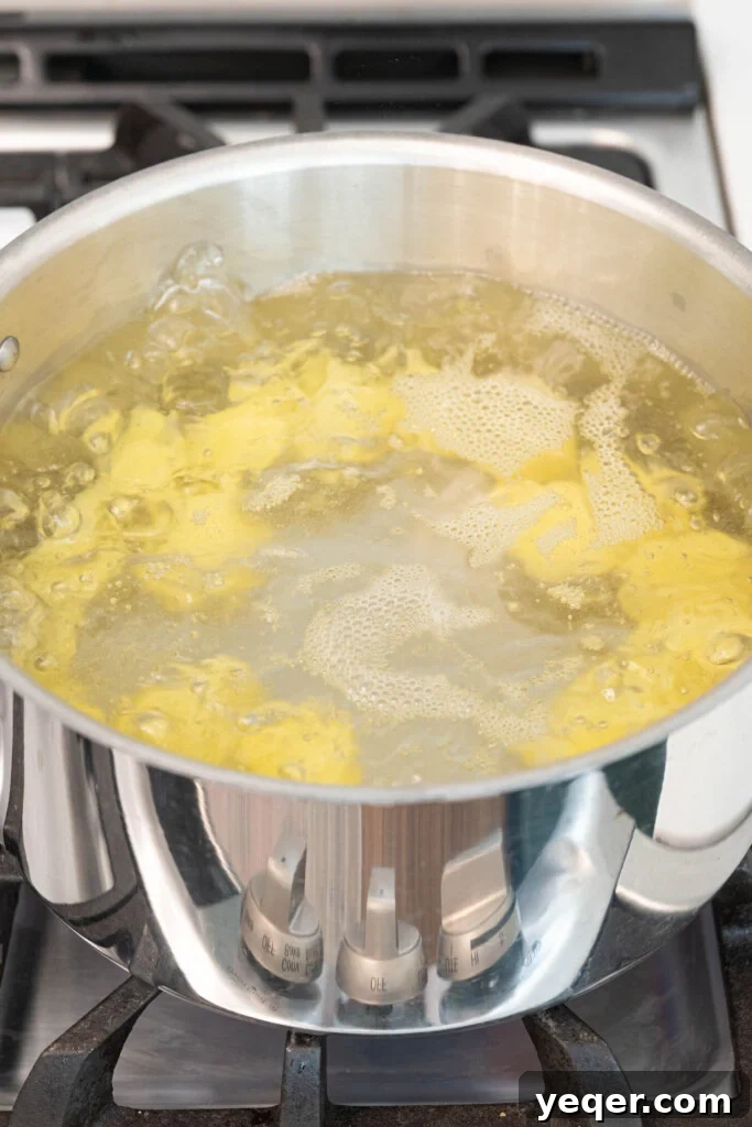 Golden Crispy Stuffed Potatoes 7 Chopped potatoes boiling vigorously in a pot of water on the stovetop.