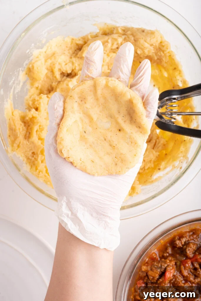 Golden Crispy Stuffed Potatoes 9 A hand holding a perfectly flattened ball of seasoned mashed potatoes, ready for filling.