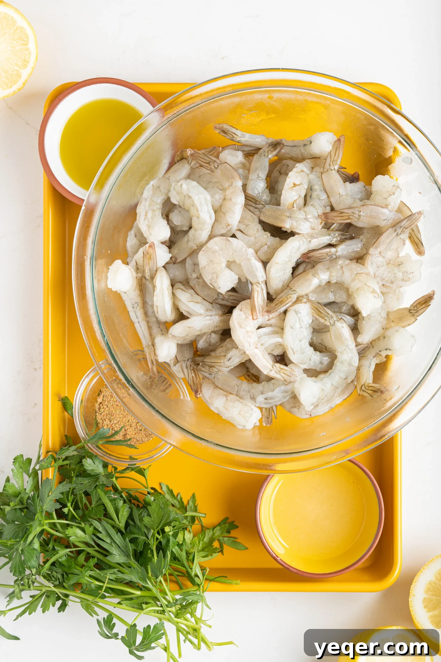 Simply Delicious 5 Ingredient Grilled Shrimp Skewers 3 bowls of raw shrimp, lemon juice, olive oil, adobo seasoning, and fresh parsley, laid out as ingredients for grilled shrimp skewers.