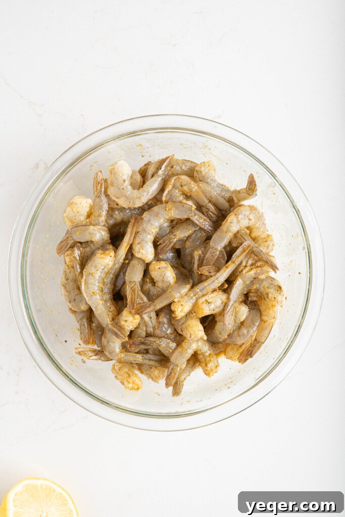 Simply Delicious 5 Ingredient Grilled Shrimp Skewers 5 A bowl filled with raw, peeled shrimp evenly coated in a rich, orange-hued adobo marinade, ready for refrigeration.