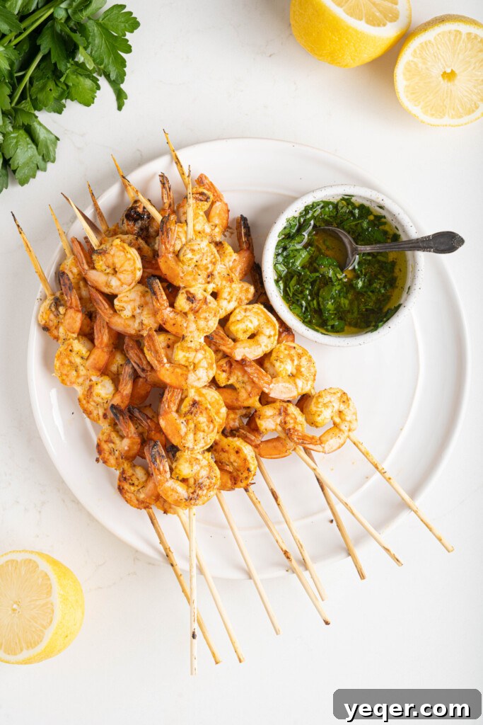 Simply Delicious 5 Ingredient Grilled Shrimp Skewers 7 Grilled shrimp skewers arranged on a plate, with a side of a green herb sauce, showcasing their perfectly cooked, opaque texture.