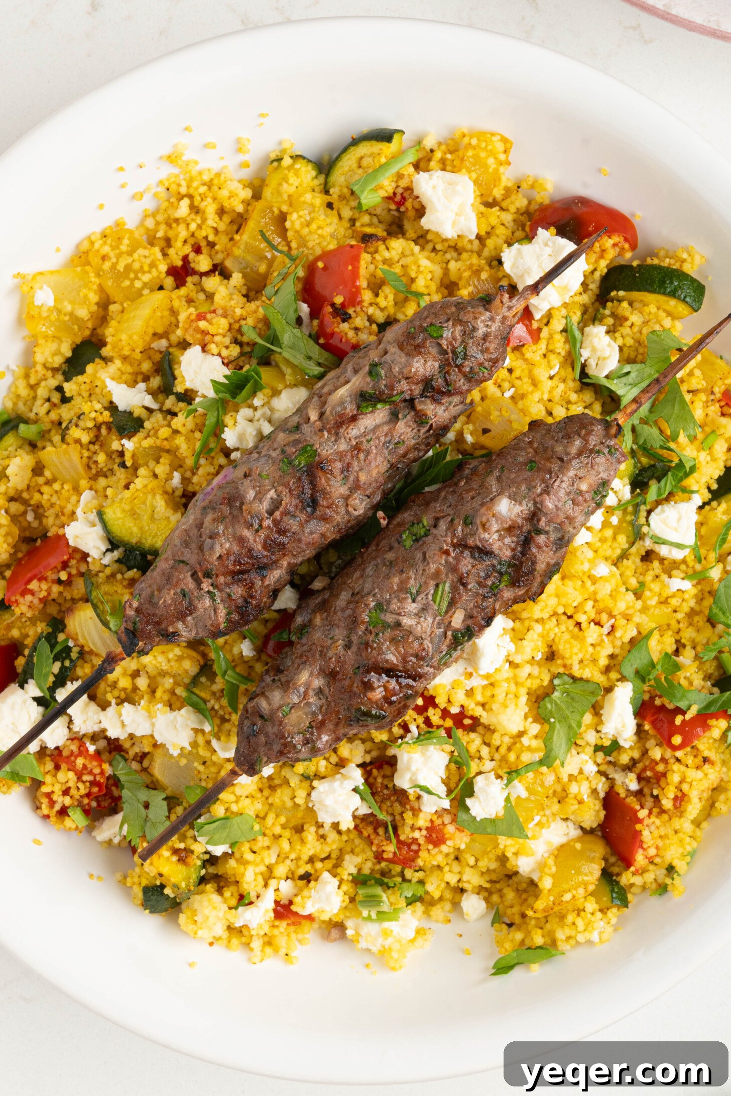 Sizzling Moroccan Kefta in 30 Minutes 11 Grilled kefta skewers served on a bed of couscous salad, ready for a delicious meal.
