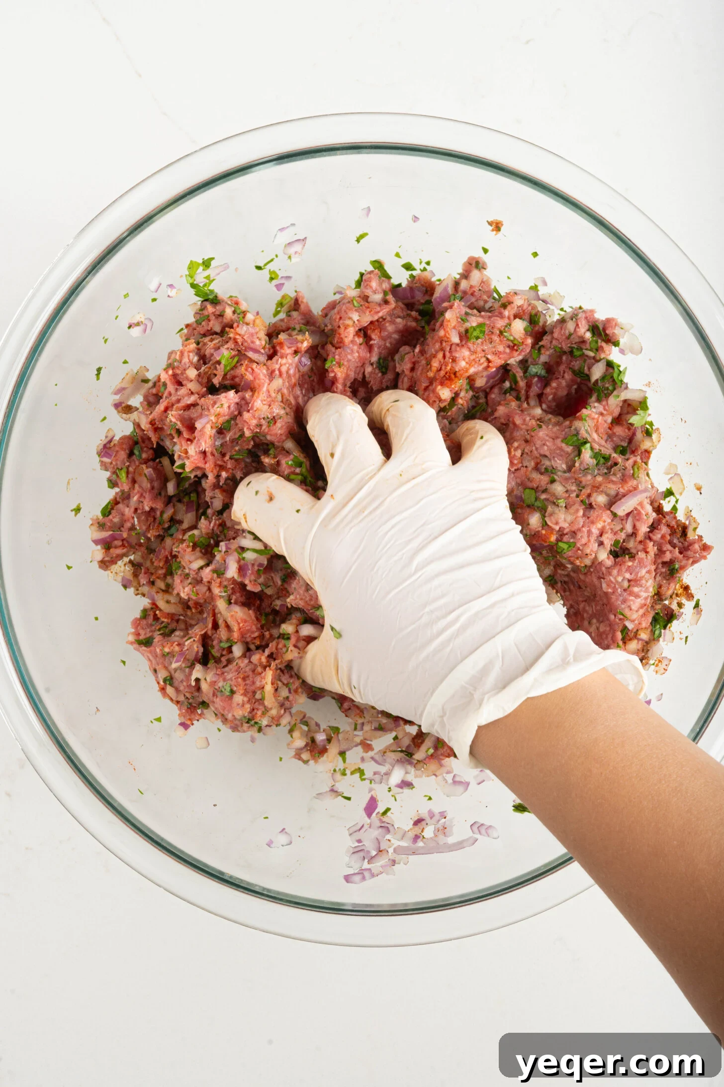 Sizzling Moroccan Kefta in 30 Minutes 4 A hand thoroughly mixing ground meat with herbs and spices in a large bowl.