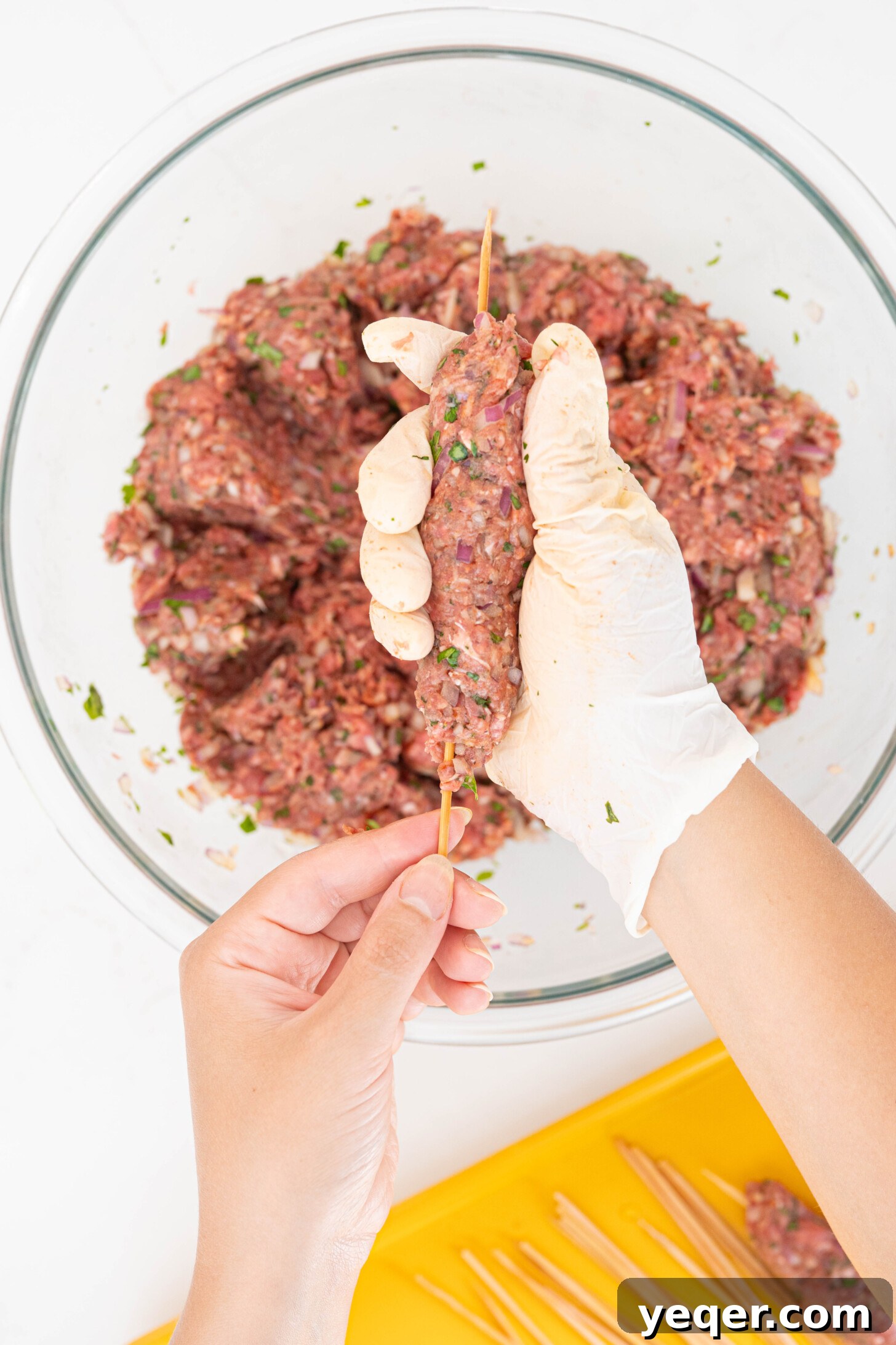 Sizzling Moroccan Kefta in 30 Minutes 6 Hands carefully forming kefta meat around a metal skewer before grilling.
