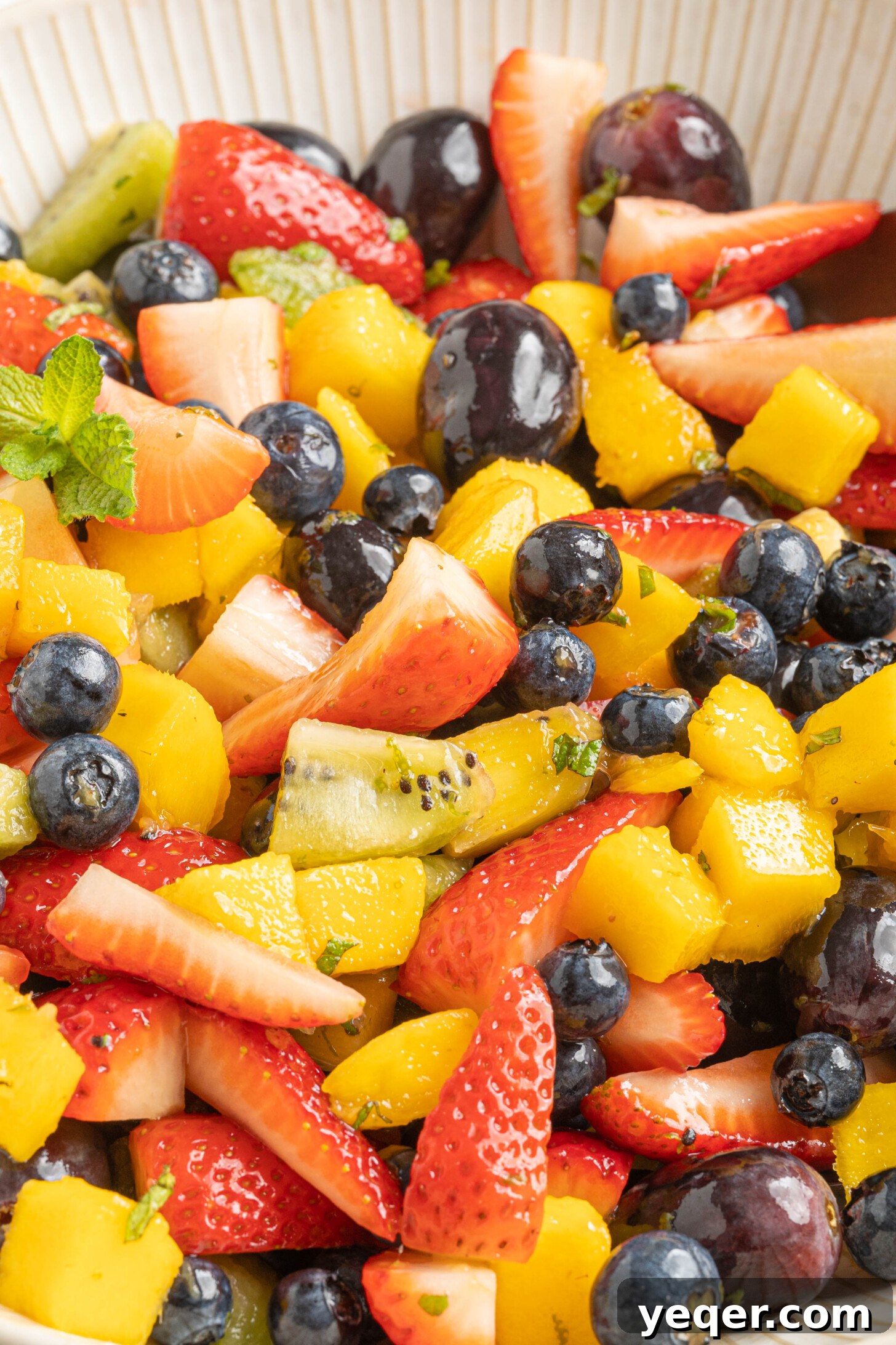 A pristine white bowl filled with the classic fruit salad, artfully arranged and ready to be enjoyed.