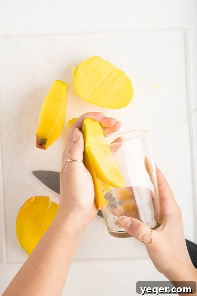 A practical method of peeling a mango using the rim of a glass, resulting in clean, neatly separated fruit flesh.