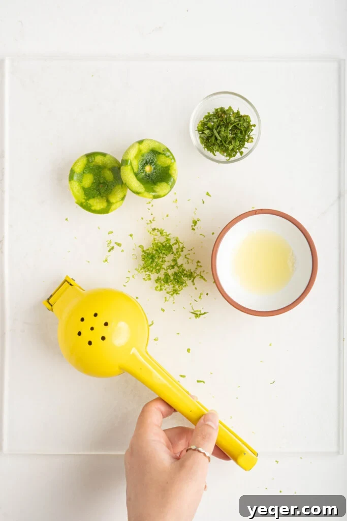 A cutting board displaying fresh lime zest, lime juice, and finely minced mint leaves, prepared to be added to the fruit salad.