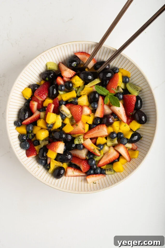 The finished classic fruit salad presented elegantly in a white bowl, ready for serving.