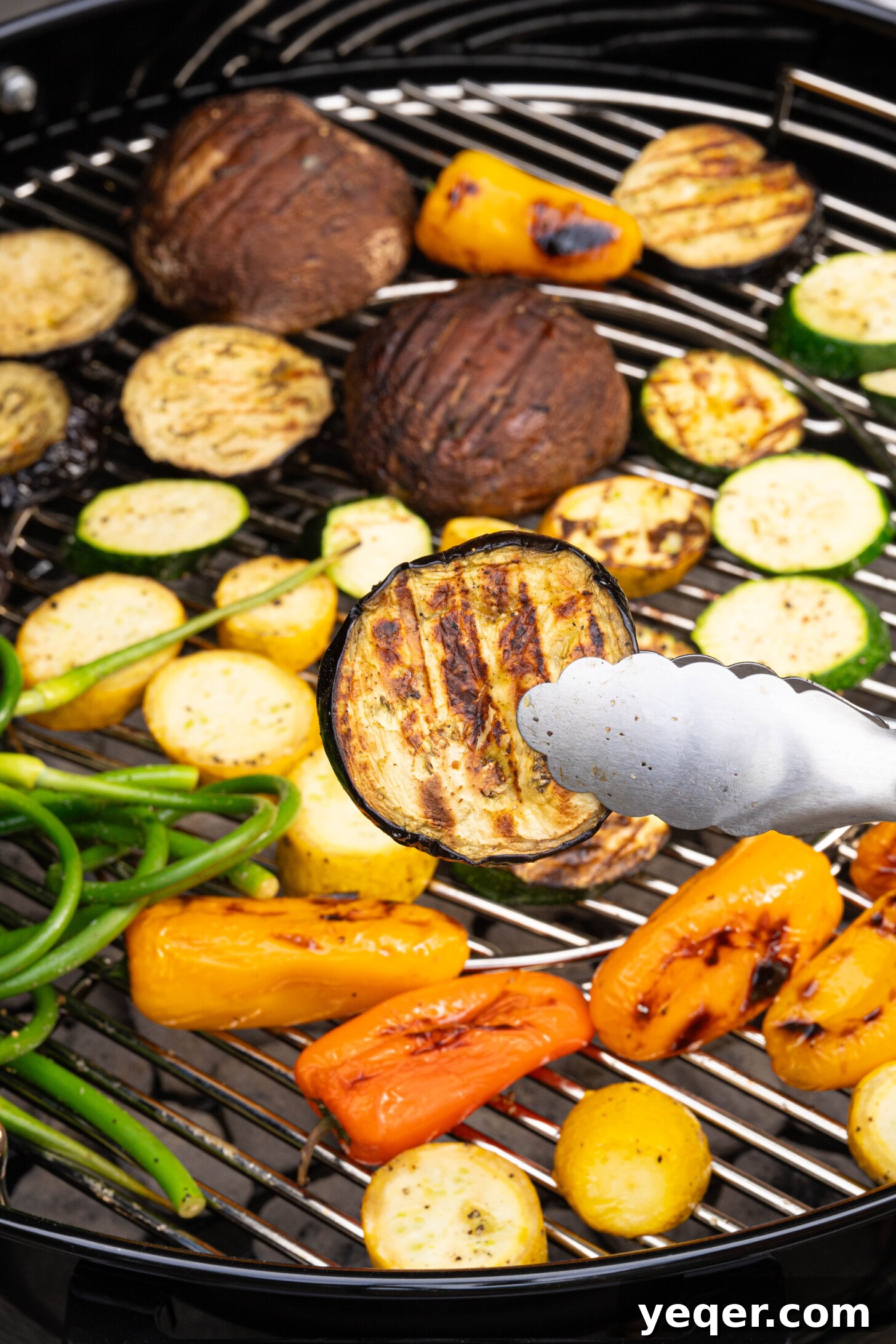 Effortless Grilled Vegetables: 3-Ingredient Marinade 11 A piece of grilled eggplant with prominent grill marks, suspended over the hot grates of a barbecue grill.