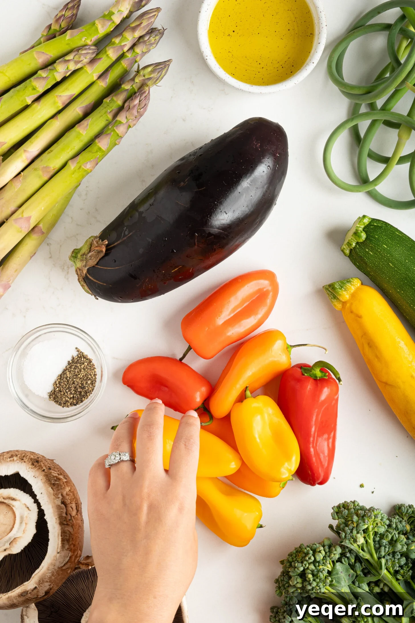 Effortless Grilled Vegetables: 3-Ingredient Marinade 13 A hand reaching for sweet mini peppers from a counter filled with a colorful array of fresh, raw vegetables.