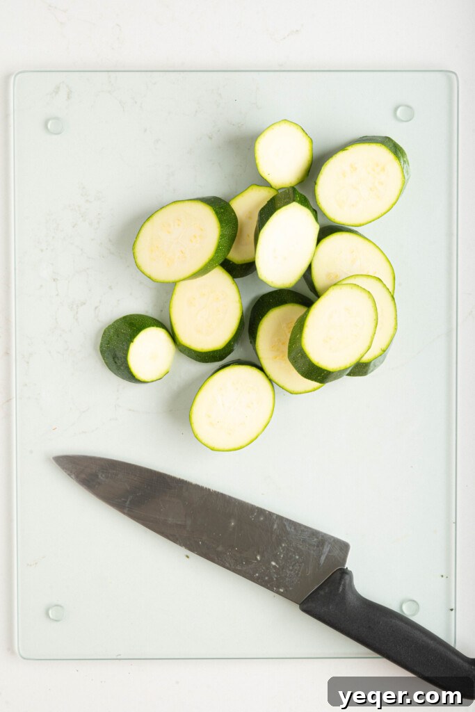 Effortless Grilled Vegetables: 3-Ingredient Marinade 5 Zucchini on a cutting board with a knife, ready to be sliced.