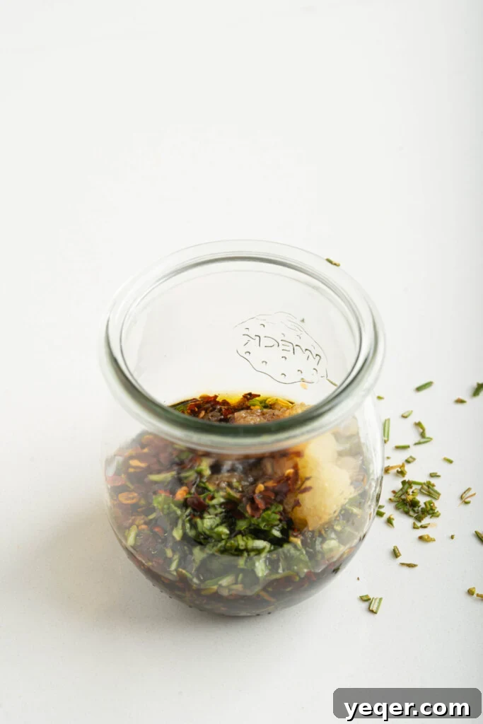 Effortless Grilled Vegetables: 3-Ingredient Marinade 8 A jar containing a freshly made dressing with herbs, garlic, olive oil, and balsamic vinegar, with a whisk resting in it.