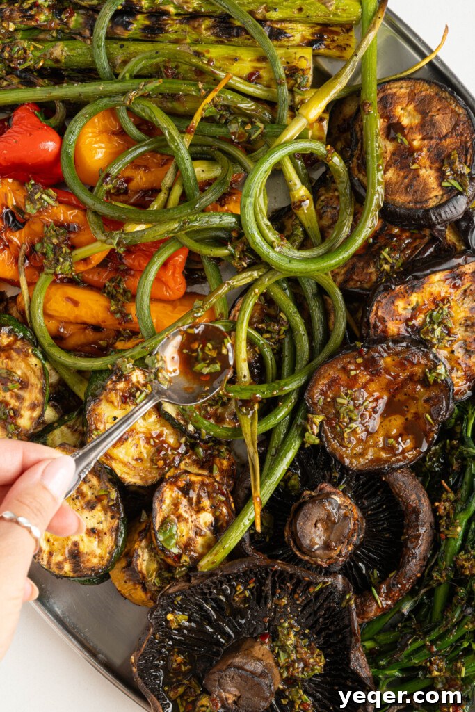 Effortless Grilled Vegetables: 3-Ingredient Marinade 10 A spoon drizzling the balsamic herb dressing over a large platter of freshly grilled mixed vegetables.