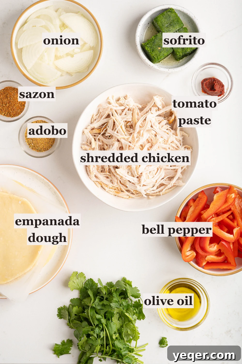 Homestyle Shredded Chicken Empanadas 3 Bowls neatly arranged with prepared ingredients for empanadas, including shredded chicken, sofrito, various spices, diced onions, and bell peppers.