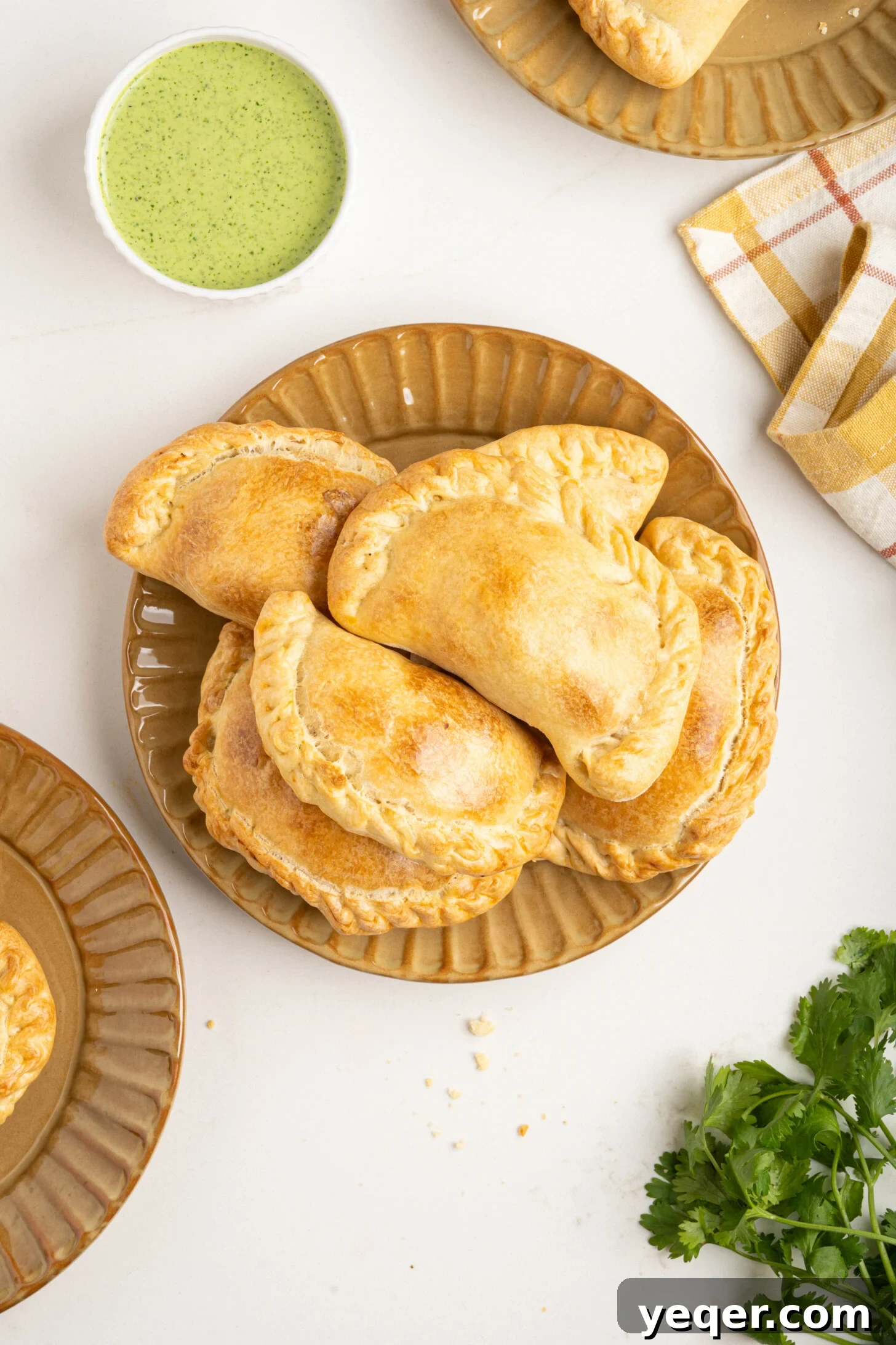 Homestyle Shredded Chicken Empanadas 11 A close-up shot of several baked chicken empanadas on a rustic wooden board, showcasing their golden crust and enticing texture.