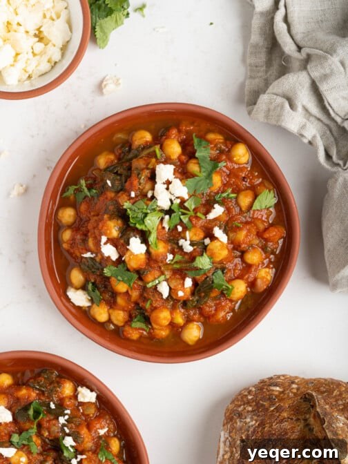 Two bowls of Moroccan stewed chickpeas, garnished with fresh herbs, ready to be served.