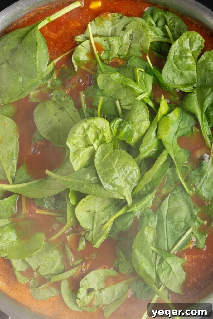 Hearty 30-Minute Moroccan Chickpea and Tomato Stew 6 Fresh spinach wilting into a pot of simmering chickpea stew.